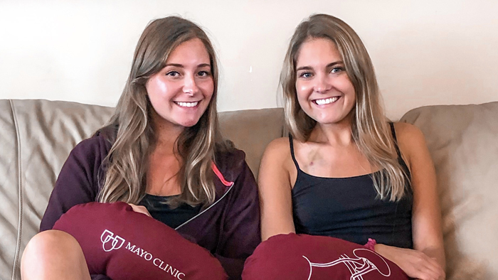 Sisters sitting on couch smiling at camera